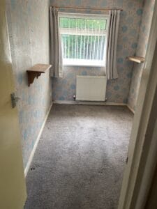 House Clearance Birmingham6 Garden Clearance A small, empty bedroom with patterned wallpaper and carpet, showing the results of a house clearance with all large items removed.