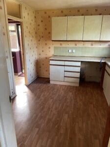 House Clearance Birmingham9 Garden Clearance An empty kitchen area with old cabinets, a backsplash, and vinyl flooring, showing the space after a kitchen strip-out or clearance of appliances.