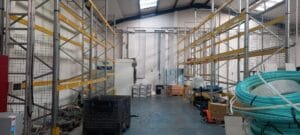 E6E59F18 5948 4951 87D2 D54Cb95C2D0E Industrial Clearance A long view of a mostly empty industrial warehouse with two long rows of tall, yellow-and-metal shelving, showing the scale of a large factory or commercial property clearance project.