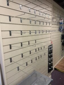 Retail Shop Clearance West Midlands1 Retail Shop Clearance A wall panel in an empty shop, lined with horizontal beige slatwall and dozens of empty silver metal display hooks. The hooks stick out into the room, showing the wall where products used to be displayed, indicating a recent clearance.