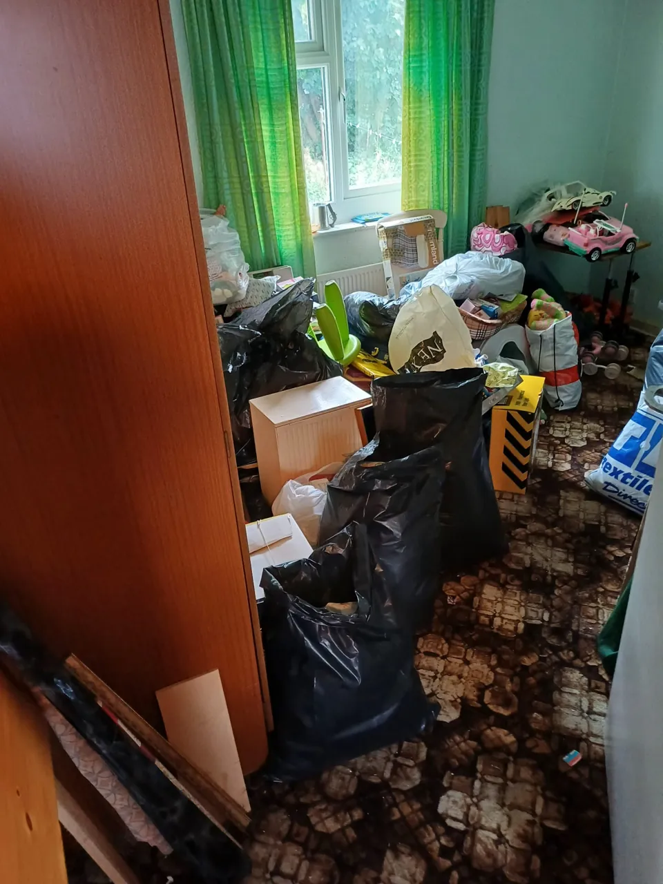 Bedroom filled with black sacks and bagged belongings awaiting clearance